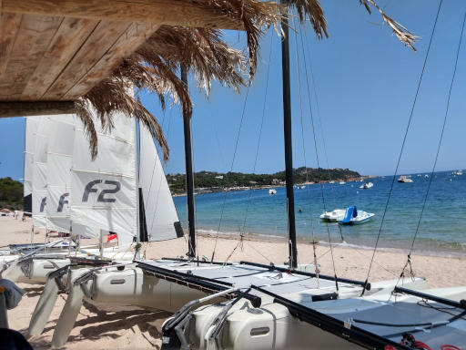 Catamarans de l'école alignés sur la plage de Cala Rossa, prêts pour une sortie de groupe
