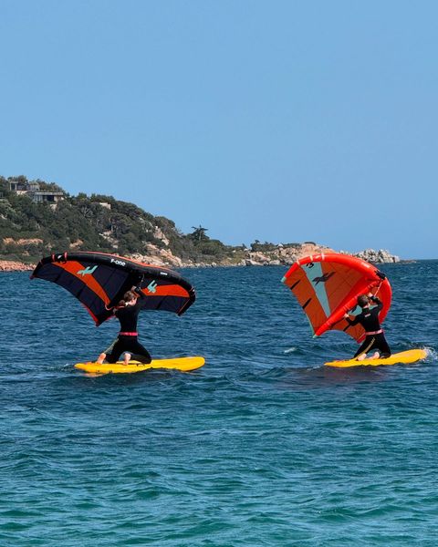 Deux élèves en wingfoil, aile en main, sur l'eau turquoise de la baie de Porto-Vecchio